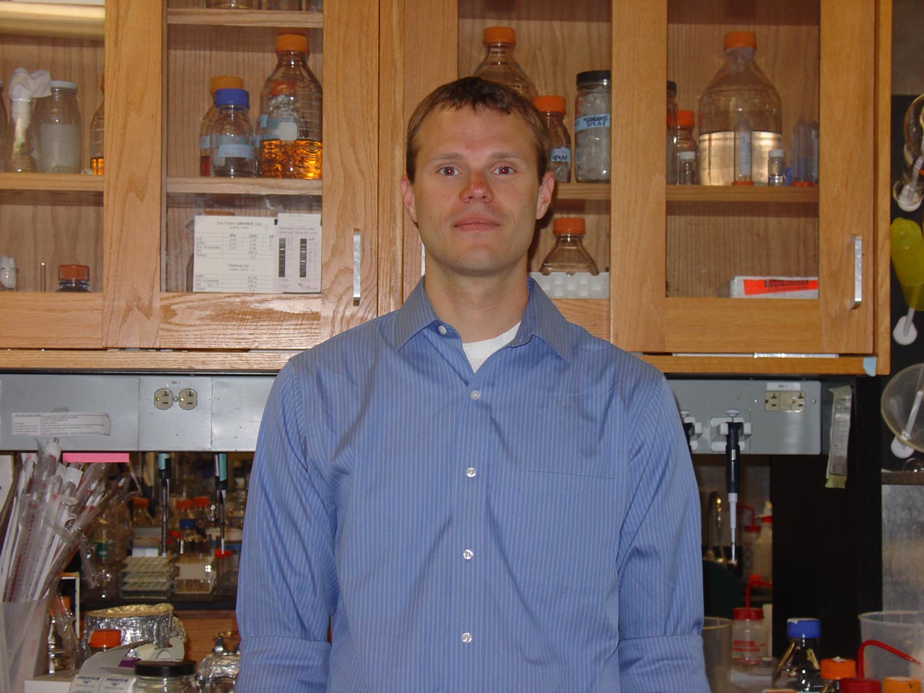 Picture of Prof. Olsen in front of a lab bench.