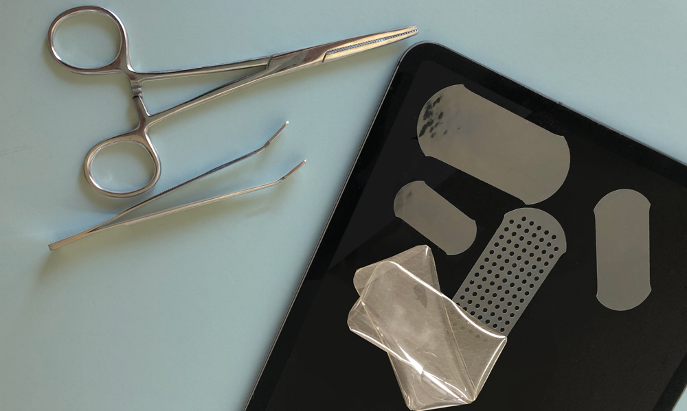 samples of double sided tissue tape on a black surface next to a pair of tweezers and hemostats
