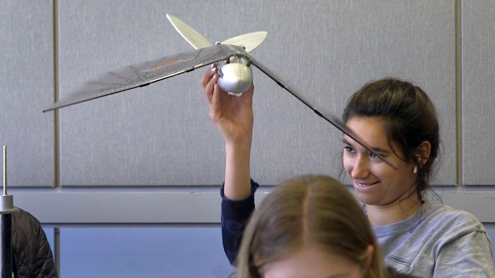a female student holds a model plane over her head