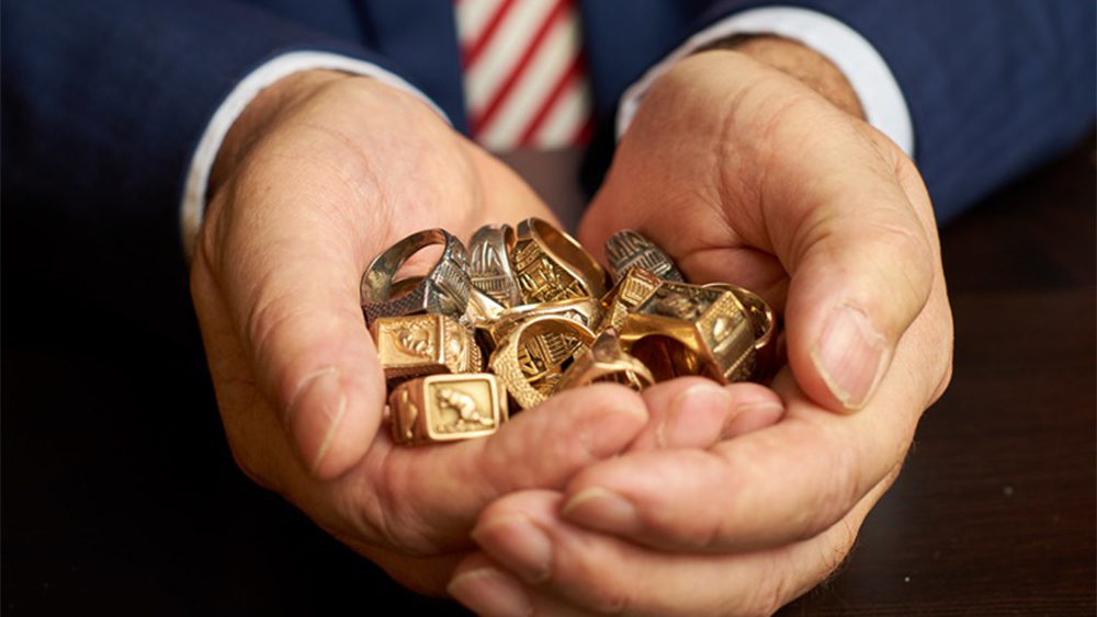 a closeup of hands holding multiple brass rat rings