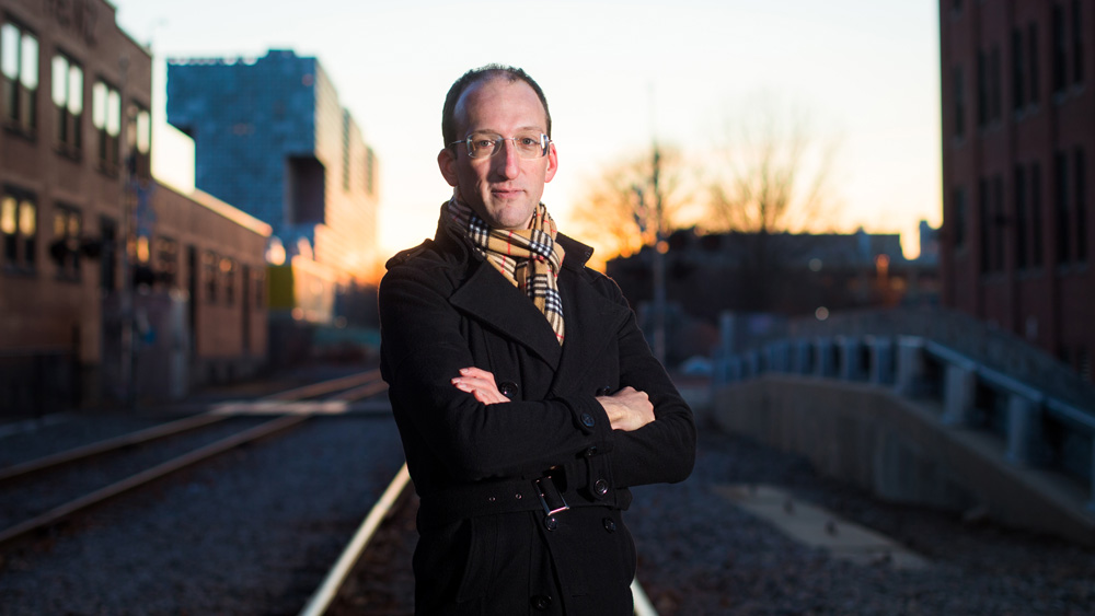 Mike Short on train tracks with Simmons Hall in distance, by Gretchen Ertl