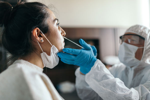  a woman getting a nasal swab covid test by a medical professional