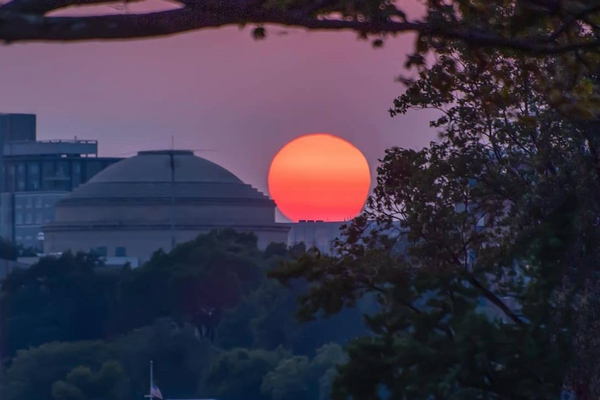 a red sun setting behind the MIT dome