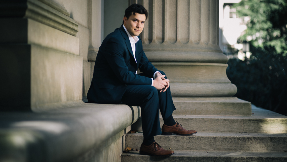 Photo of Max Williamson sitting near MIT's iconic columns 