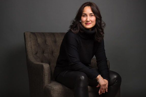 Photo of Cynthia Breazeal sitting on grey chair with grey background