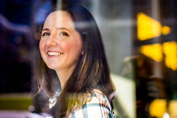 Sophia Mittman smiling through a window lit by sunlight