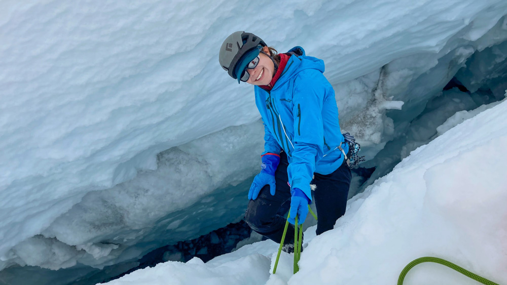 Joanna Millstein sitting on the edge of an icy crevasse