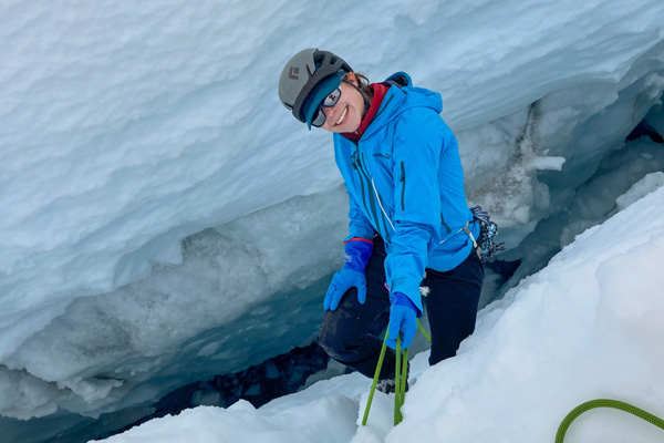 Joanna Millstein sitting on the edge of an icy crevasse