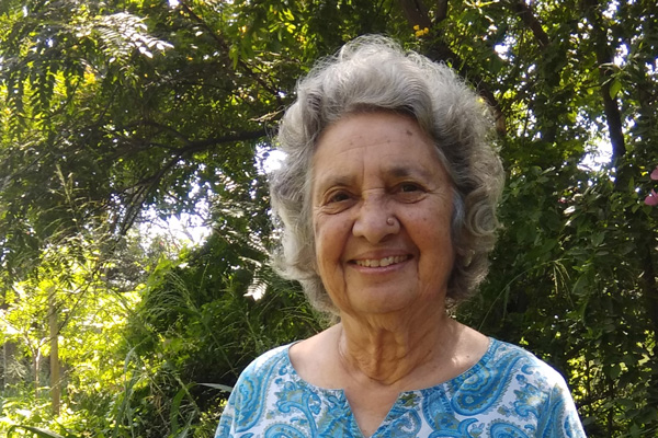 Almitra Patel standing outside in front of green, leafy trees