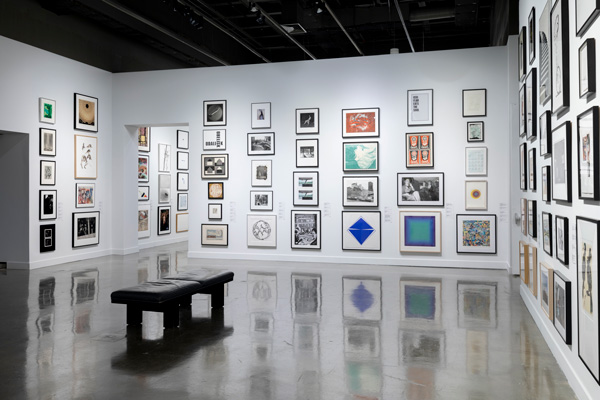 Gallery with salon-style hanging of dozens of artworks