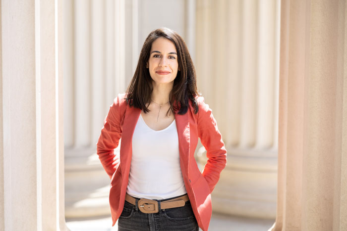 Juncal Arbelaiz wears a red jacket and stands outside, with MIT columns in background.
