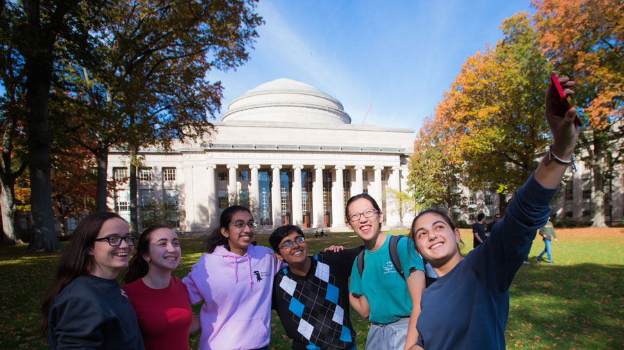 Group of students take a group selfie in Killian Court with Great Dome in background