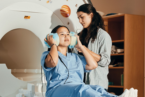 Saima Malik-Moraleda prepares a lab colleague for an MRI imaging session and reviews brain images