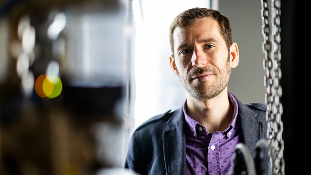 James LeBeau portrait inside lab, framed by blurry lab objects in foreground