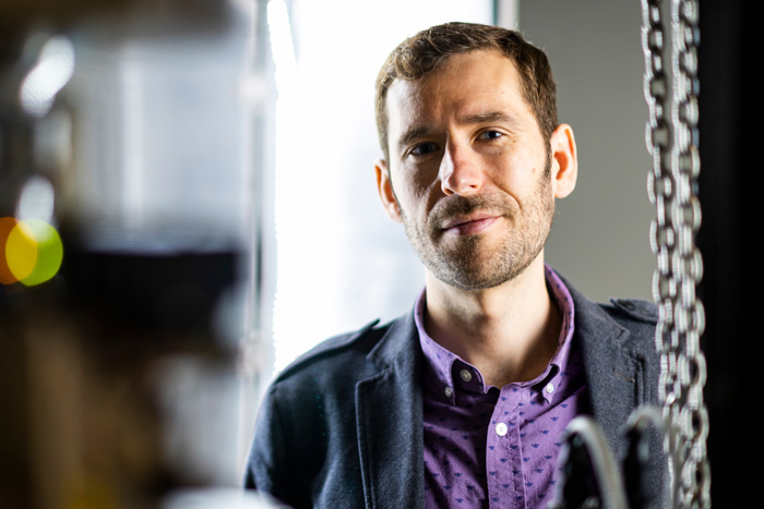 James LeBeau portrait inside lab, framed by blurry lab objects in foreground