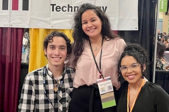 3 people smile while tabling a conference