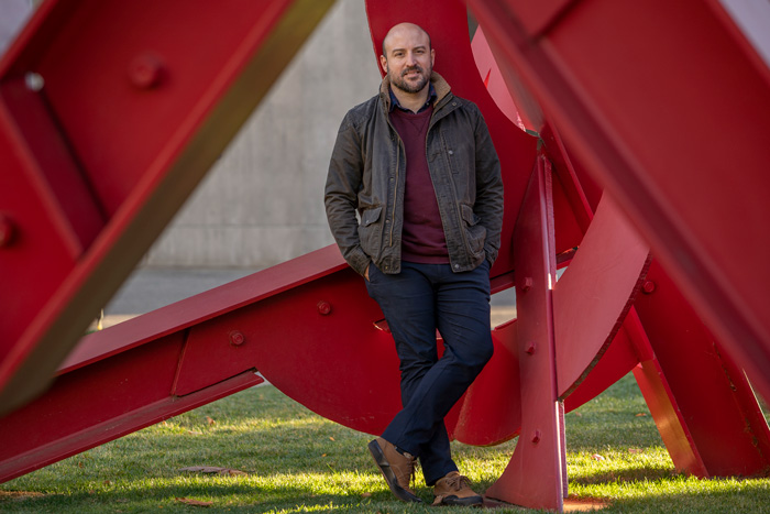 Otto Cordero stands inside the outdoor red sculpture, Aesop's Fables, by Mark di Suvero.