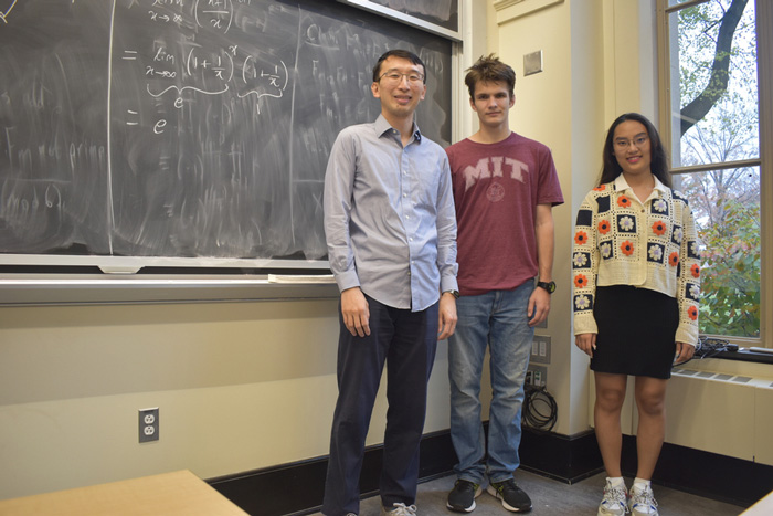 Professor Yufei Zhao (left) stands with sophomore Tomasz Ślusarczyk (center) and senior Dain Kim in class