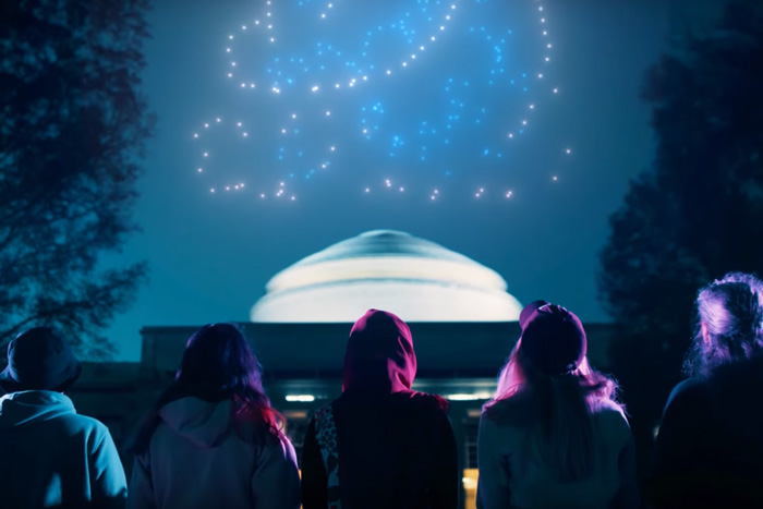 5 people look at the Great Dome as drones prepare to create various scenes in the sky