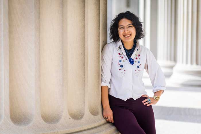 Amelia Dogan leaning against a large stone column at MIT