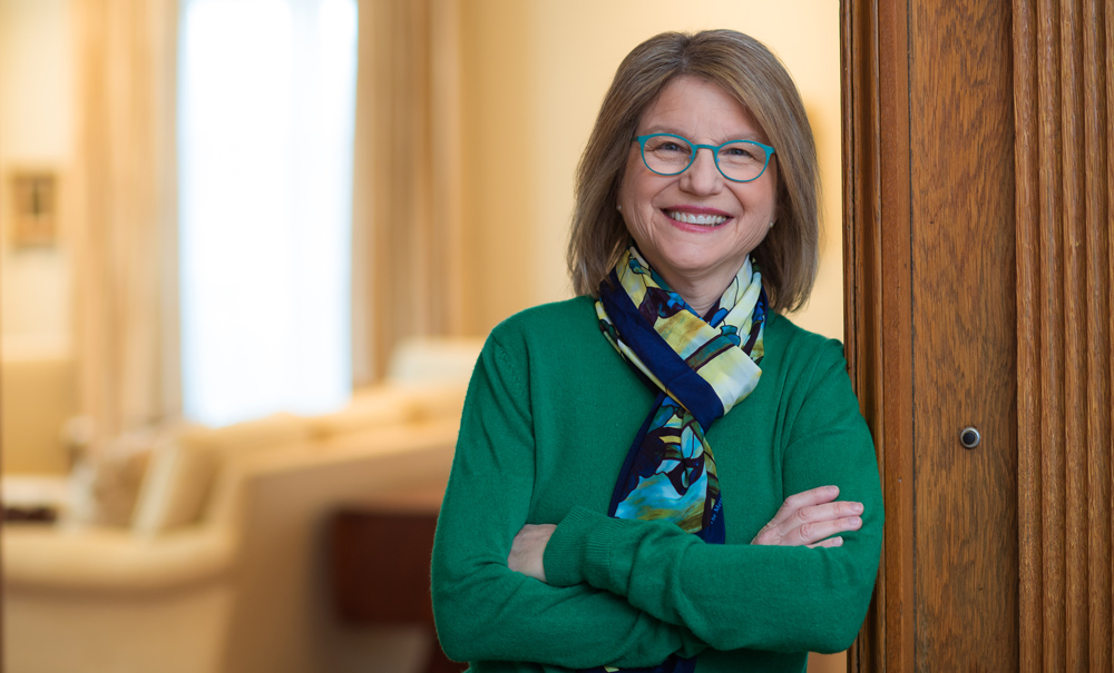 Sally Kornbluth next to a dark wooden wall