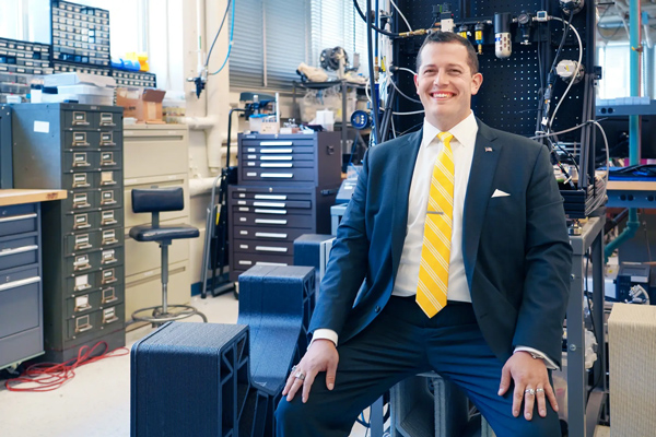 MIT Design Fellow Dr. AJ Perez, sitting on a piece of 3D-printed building foundation