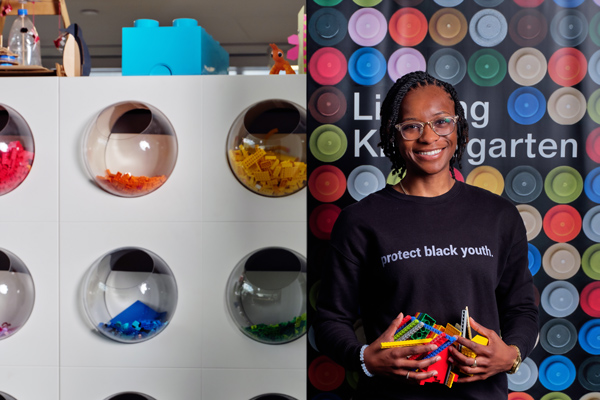 Sadler smiles while holding lots of Legos. Her shirt says, “protect black youth.” The background has a sign that says “Lifelong Kindergarten.”