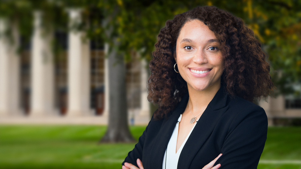 Photo collage shows Sydney Johnson portrait with arms crossed, and blurry Killian Court in background.