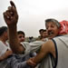 An Iraqi man gestures as he greets his son after he was being released from the Abu Ghraib prison in Baghdad, Iraq, Friday, May 28, 2004. Hundreds of relatives who had been following the convoy with detainees stopped on the highway in Baghdad and swarmed around the vehicles. Prisoners then got off the buses and went home with their families.(AP Photo/Anja Niedringhaus)