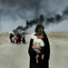 An Iraqi woman carries her young child on the outskirts of Basra as she flees with others from this southern Iraqi town Sunday, March 30, 2003.  (AP Photo/Anja Niedringhaus)