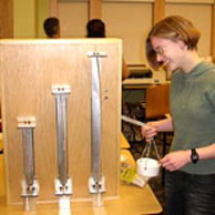 MIT freshman Ellen Cappo demonstrates a column buckling exhibit.