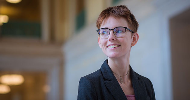 Headshot of grad student Amelia Trainer standing inside a lobby of an MIT building, background in soft focus, MIT