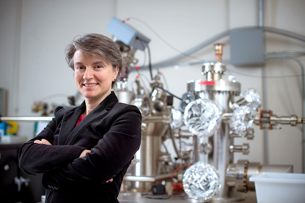 Female faculty member in front of lab equipment and instrumentation, MIT