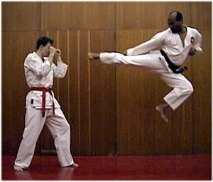 photo: male black belt flying side kick at partner