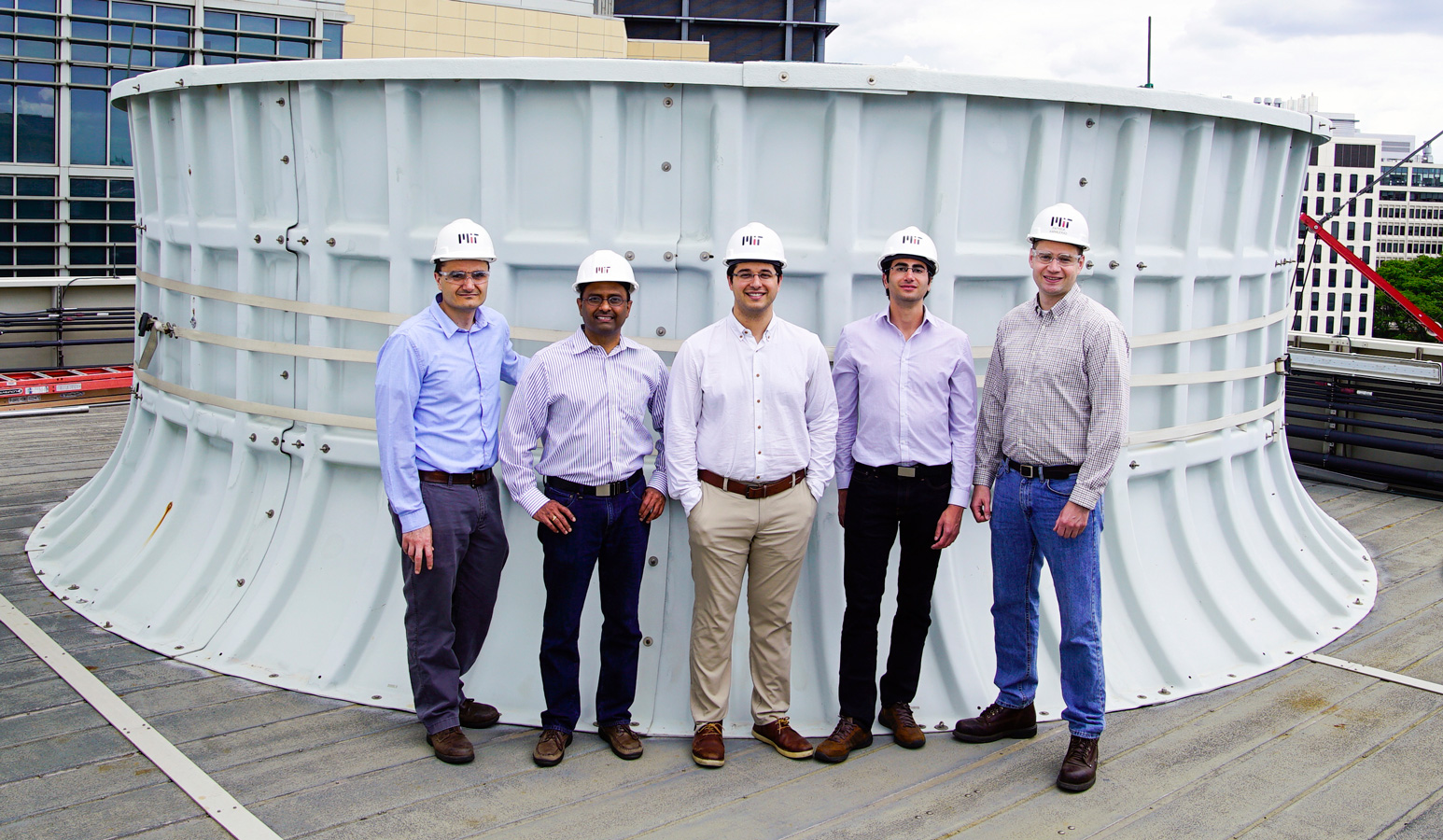 On the roof of the Central Utility Plant building, standing in front of one of the cooling towers, are (left to right): Seth Kinderman, Central Utility Plant engineering manager; Kripa Varanasi, associate professor of mechanical engineering; recent doctoral graduates Karim Khalil and Maher Damak; and Patrick Karalekas, plant engineer, Central Utilities Plant.