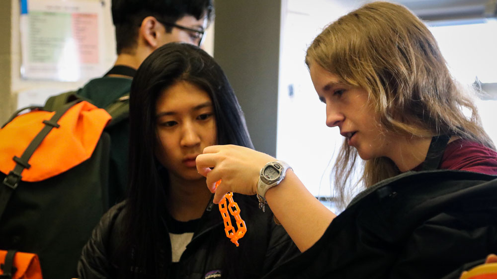 two students accepted to MIT looking at a 3-D printed chain