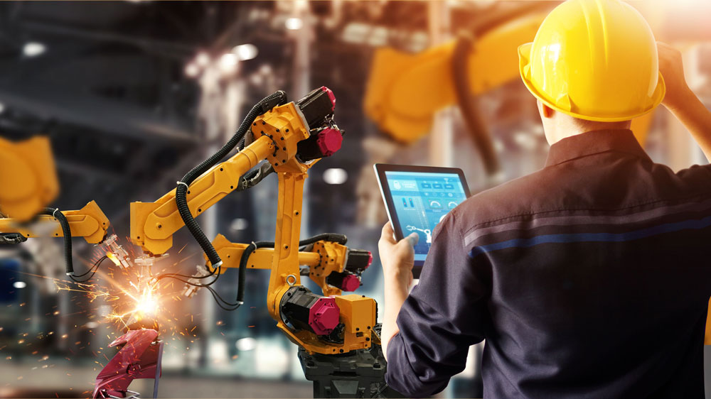 a worker standing next to a robotic arm