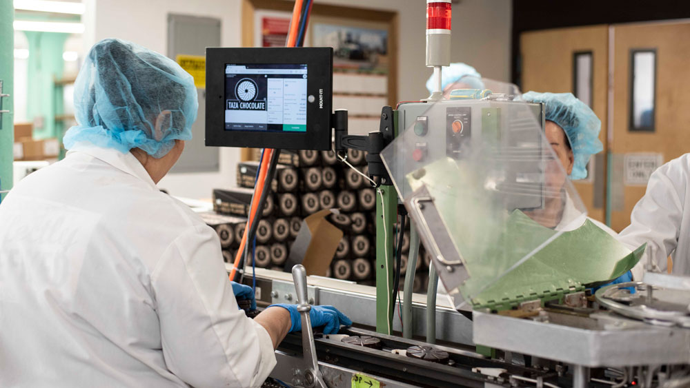 Workers at a chocolate making plant using Tulip software on the production line