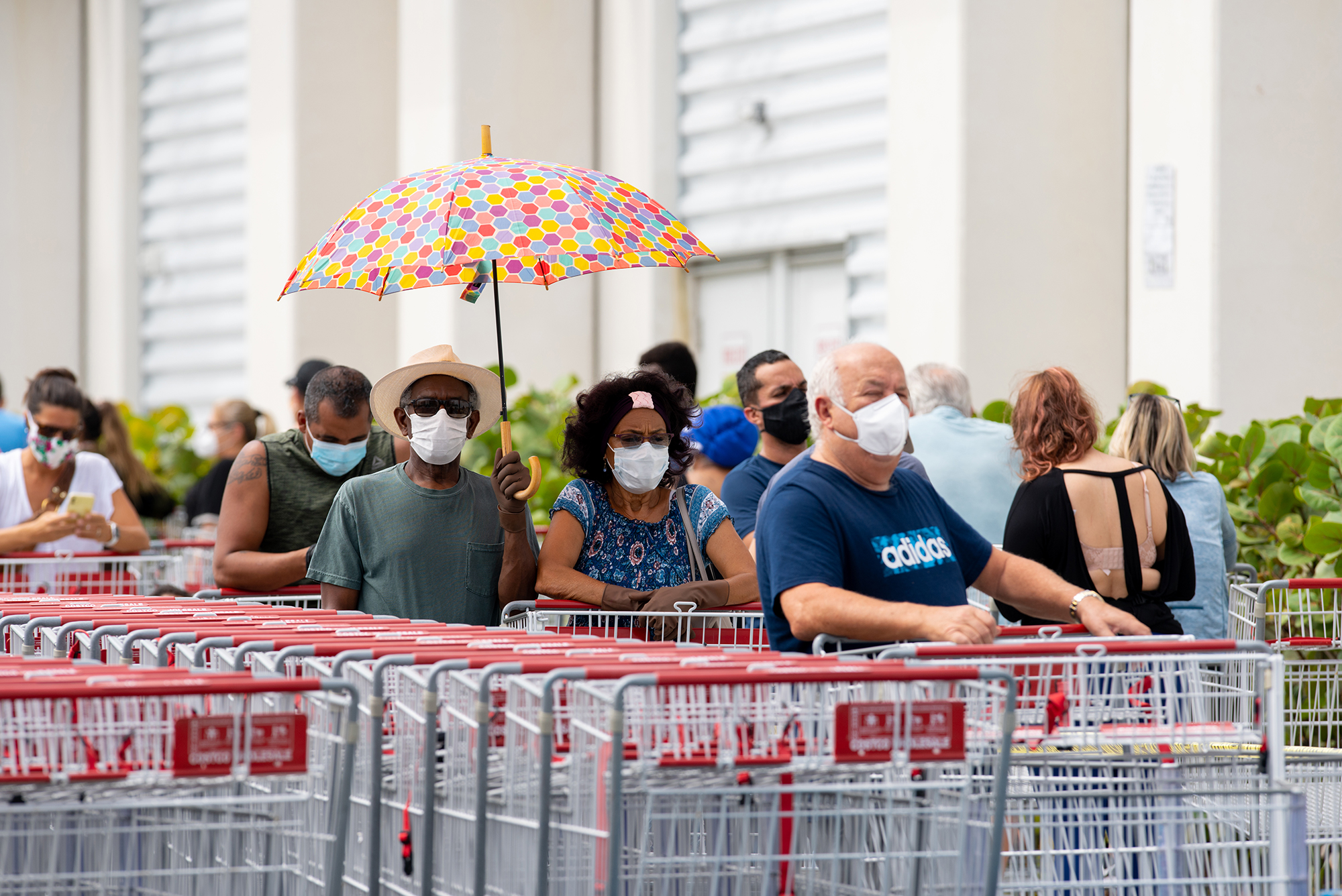 Masked customers waiting outside a store