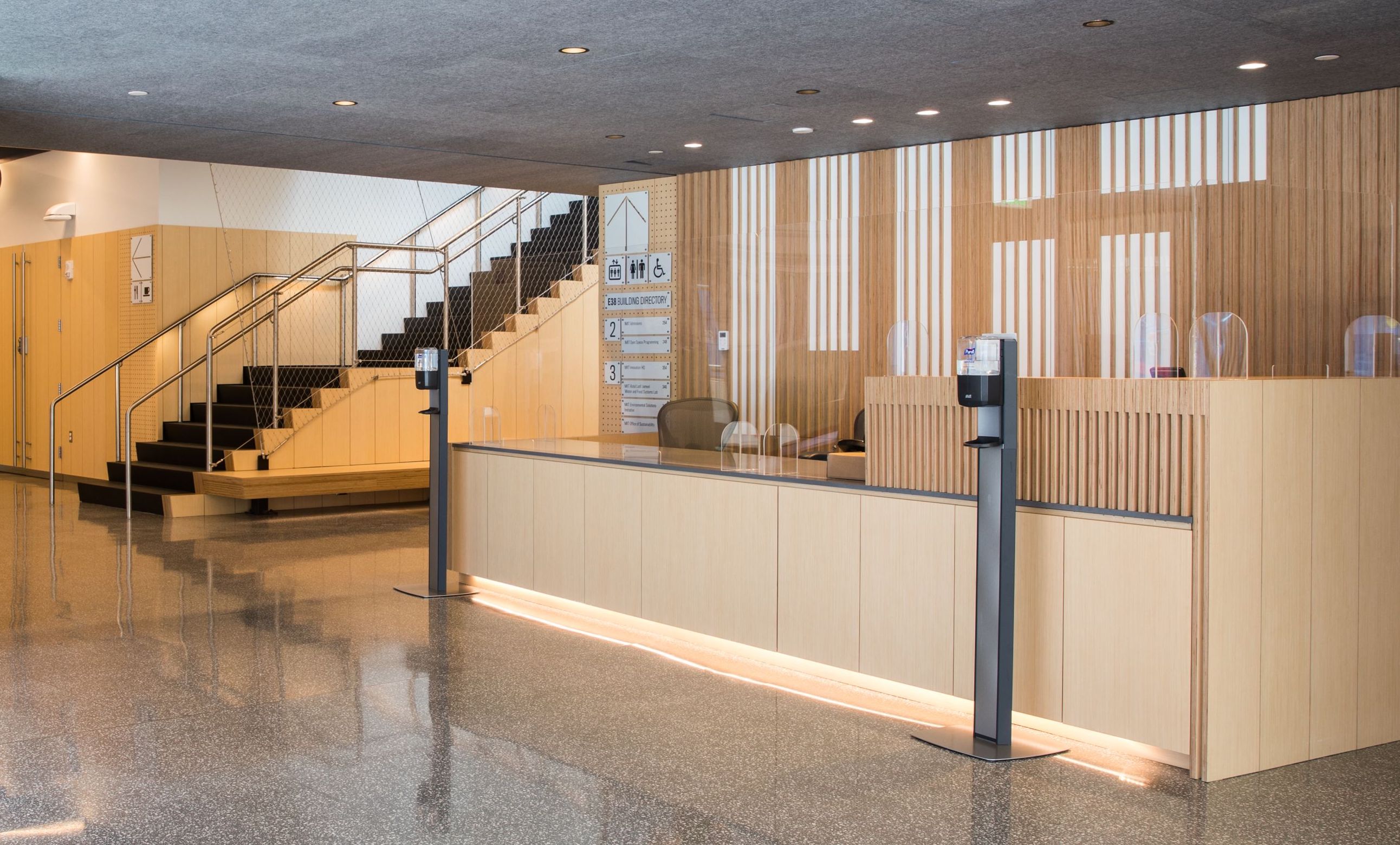 Front desk of the MIT Welcome Center. There is a large MIT logo on the back wall.