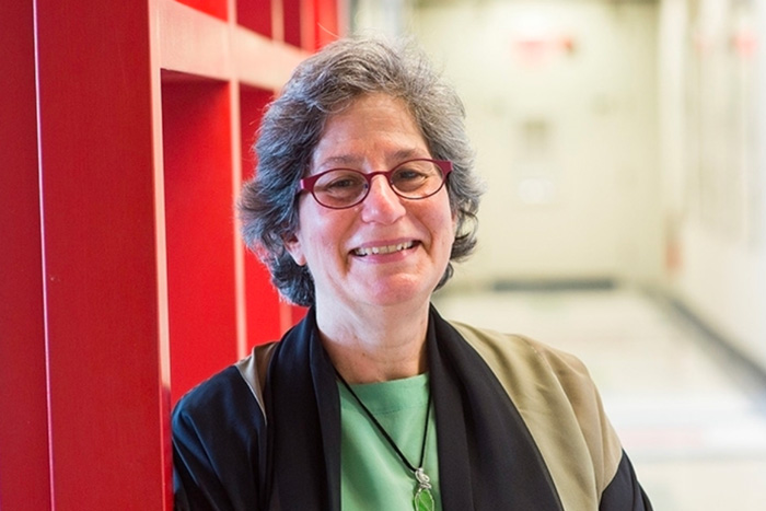 MIT Professor Susan Solomon smiles with red hallway wall in background