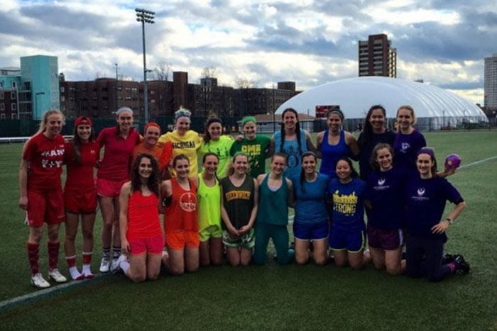 The MIT lacrosse team poses to make a rainbow with their colorful clothing