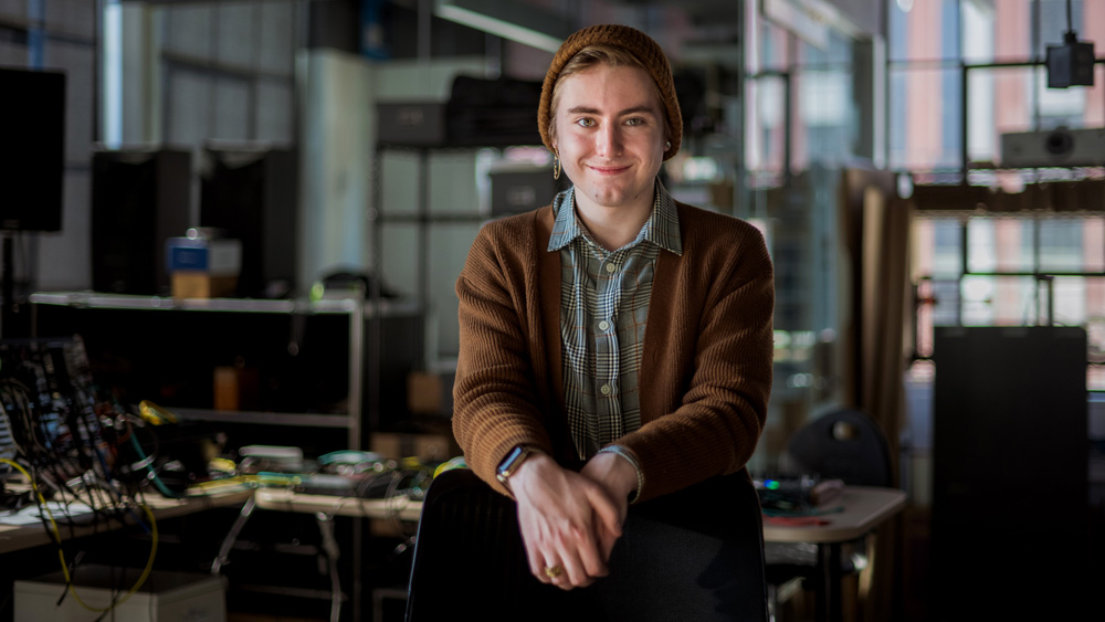 Photo of Tanner Bonner sitting on desk with synthesizers