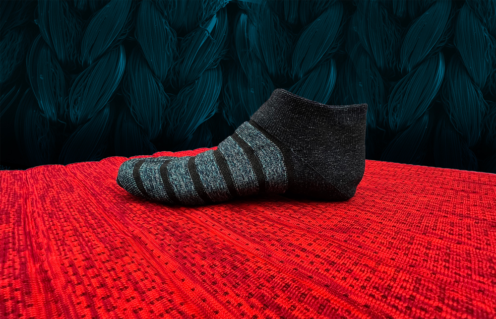 A black sock on a red mat both made from a 3-D knitting process that allows them to sense motion