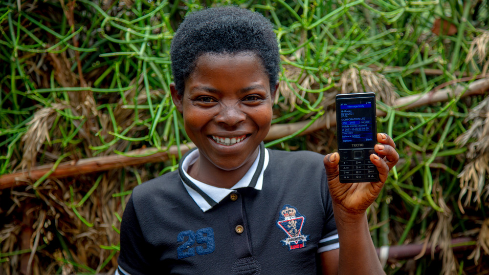 A person holds a flip-phone displaying a message from GiveDirectly