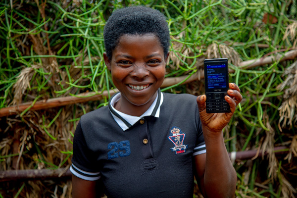 A person holds a flip-phone displaying a message from GiveDirectly