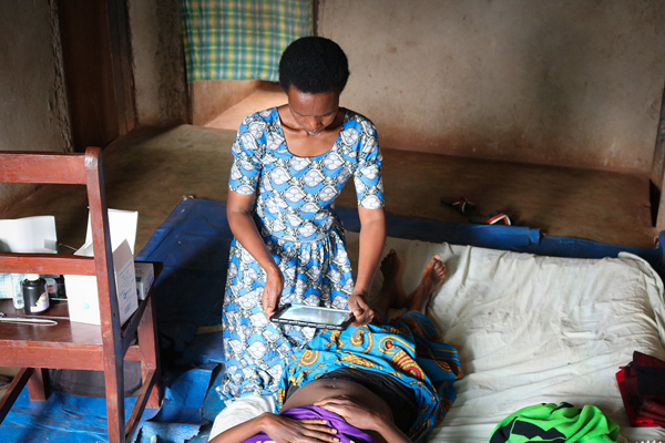 A woman holding a tablet over the C-section incision of a woman lying down