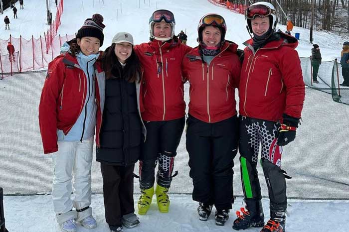 5 people pose for group photo on the slopes