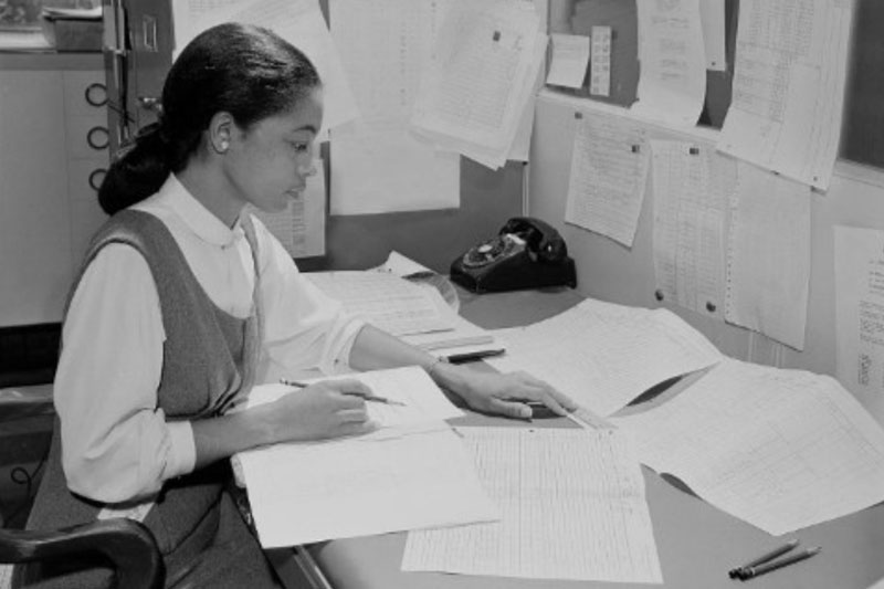 Monochrome photo of Inez Hazel at desk analyzing documents