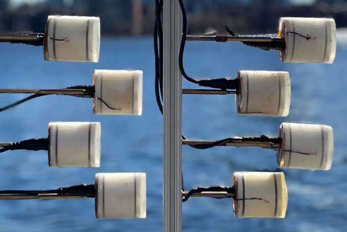 8 piezoelectric transducers look like toilet paper rolls and are attached to poles, near water.